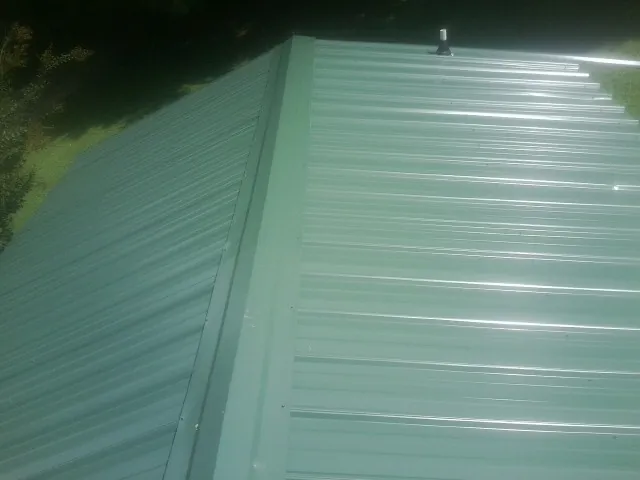 New green metal panels meeting at the ridge of a roof — Flat Roof Repair work by our crew in Carbon Hill
