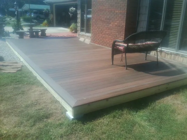 New wood deck and wicker chair beside a brick house in Carbon Hill