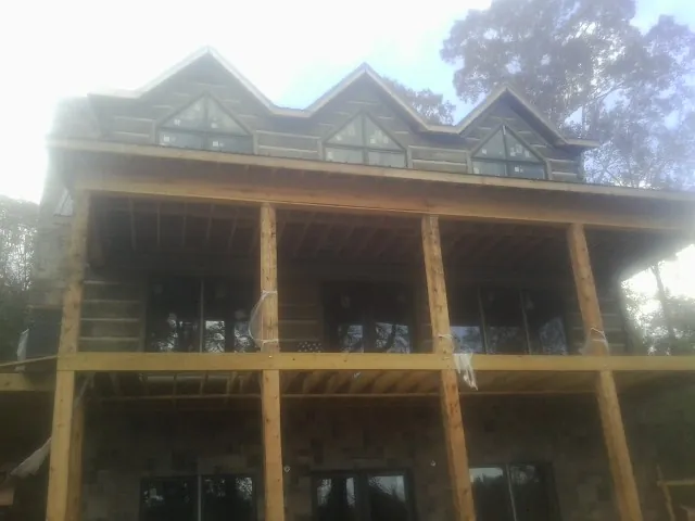 Dormers and porch framing on a large log home under construction — Roof Coating work by our crew in Carbon Hill