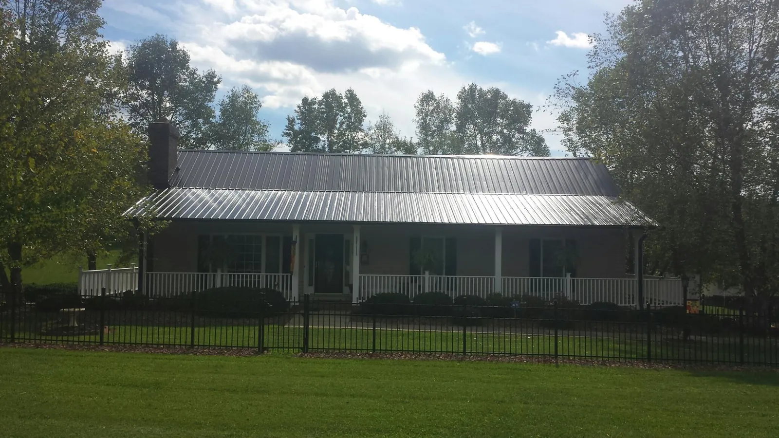 Gray metal roof on a brick ranch with a full width front porch — Gutter Guard Installation work by our crew in Carbon Hill